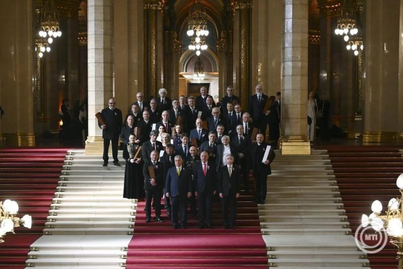 Sulyok Tamás köztársasági elnök Orbán Viktor miniszterelnök és Kövér László, az Országgyűlés elnöke társaságában adta át az elismeréseket.Az ünnepségen rész vett Áder János és Schmitt Pál volt köztársasági elnök, valamint Hankó Balázs kulturális és innovációs miniszter.A díjazottak csoportképe a Kossuth- és Széchenyi-díjak ünnepélyes átadásán, az 1848-49-es forradalom és szabadságharc évfordulója alkalmából az Országházban 2026. március 14-én. Elöl Orbán Viktor miniszterelnök, Sulyok Tamás köztársasági elnök és Kövér László, az Országgyűlés elnöke (b-j). MTI/Illyés Tibor